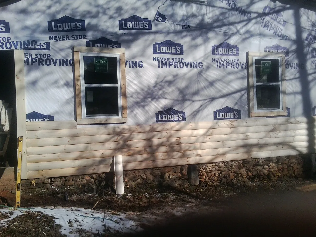 House wrap and new log siding going up on an exterior wall in Groton