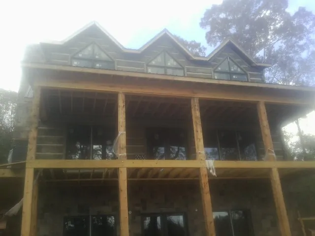 Dormers and porch framing on a large log home under construction — Roof Coating work by our crew in Groton