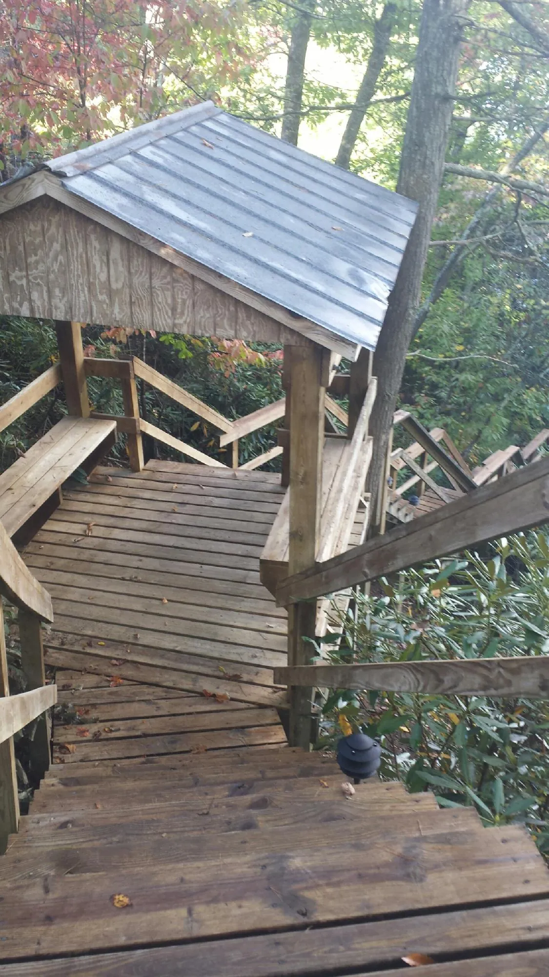 Metal roofed shelter over wooden steps on a wooded walkway — Skylight Repair & Installation work by our crew in Groton