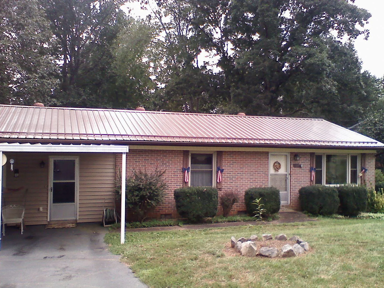 Bronze metal roof and carport on a brick ranch home — Roof Repair work by our crew in Groton